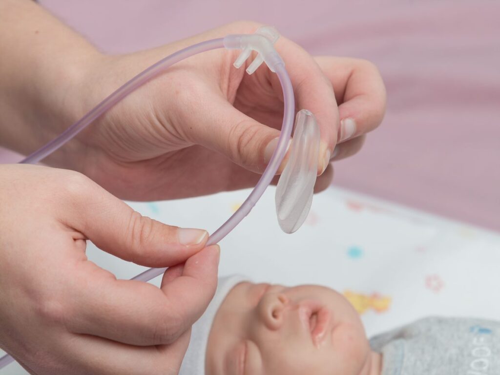 model of a baby being connected to Armstrong Medical device for HFOT using a neonatal nasal cannula