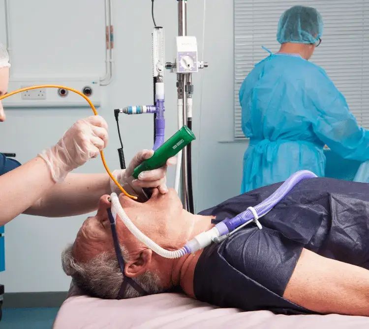 A patient lying in a hospital setting being intubated with an AviAir bougie device and laryngoscope by Armstrong Medical. IMage used on the page explaining perioperative humidification